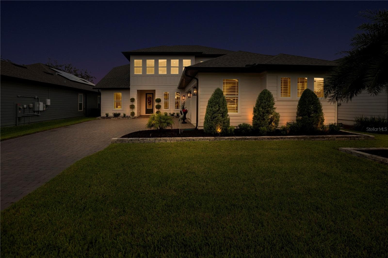 Twilight front view showcases the home’s welcoming entrance and landscape lighting. - 17600 LAKE STAR RD, WINTER GARDEN