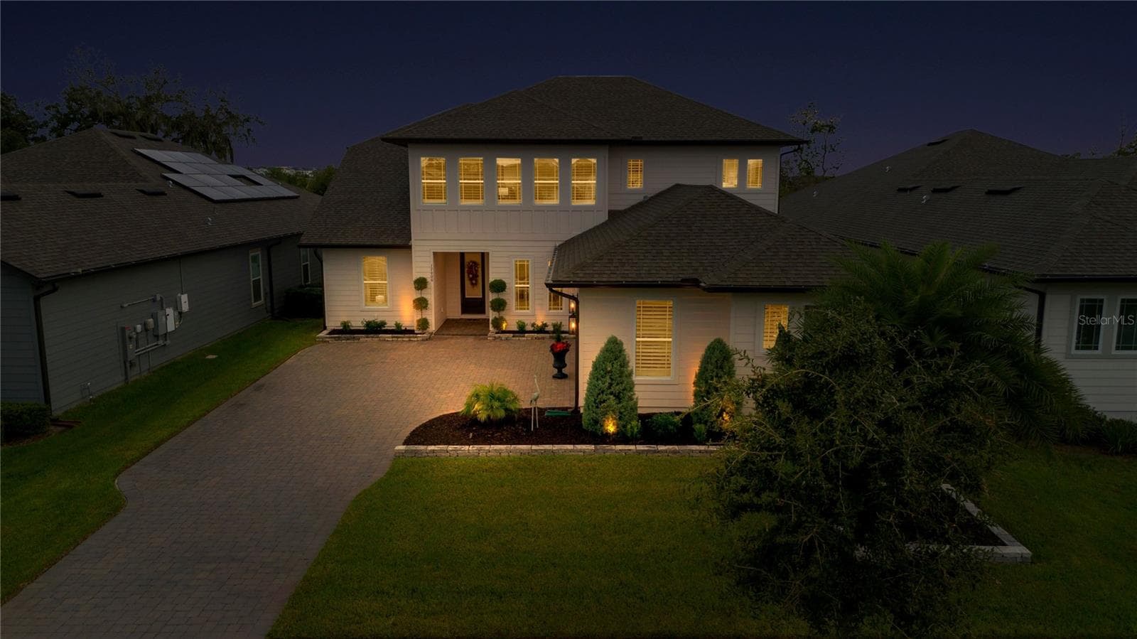Elevated evening view highlights the front entrance, driveway and landscape lighting. - 17600 LAKE STAR RD, WINTER GARDEN