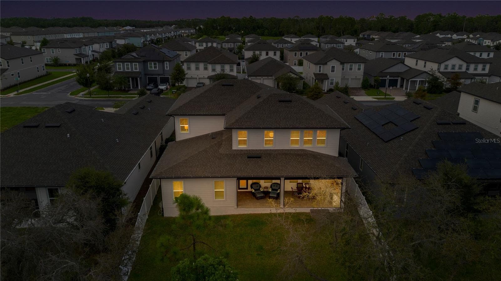 Rear aerial at twilight captures the backyard and warmly illuminated covered lanai. - 17600 LAKE STAR RD, WINTER GARDEN