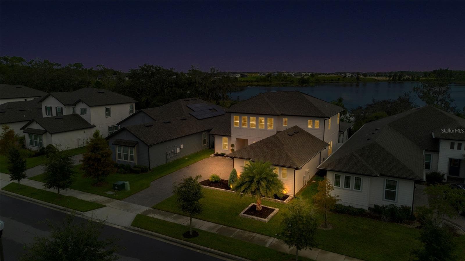 Angled twilight aerial highlights the home’s exterior lighting and scenic surroundings. - 17600 LAKE STAR RD, WINTER GARDEN