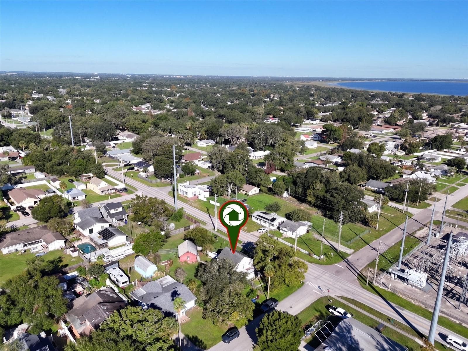 Aerial view showcasing this charming farmhouse situated on an expansive .34-ACRE CORNER LOT with a FENCED BACKYARD, BARN WITH ELECTRICITY, and an abundance of edible fruit trees, plants, and herbs. Enjoy the beauty of a well-established neighborhood with mature trees and the added bonus of a nearby lake! - 1901 10TH ST, ST CLOUD