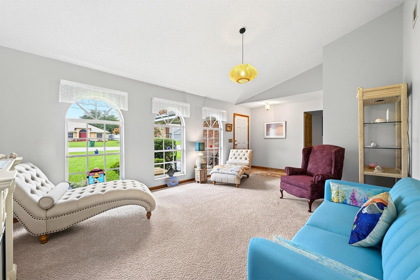Step inside to a formal Living Room featuring plush carpeting and three ELEGANT ARCHED WINDOWS that fill the space with natural light. - 2163 NEWMARK DR, DELTONA