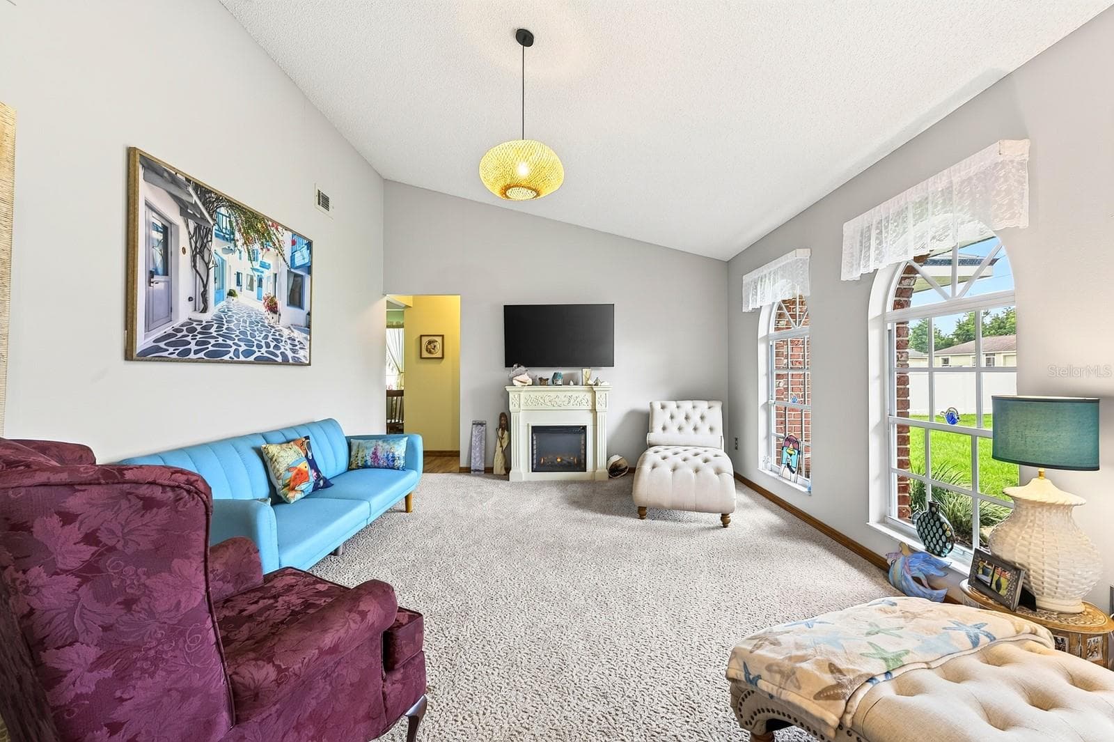 Step inside to a formal Living Room featuring plush carpeting and three ELEGANT ARCHED WINDOWS that fill the space with natural light. - 2163 NEWMARK DR, DELTONA