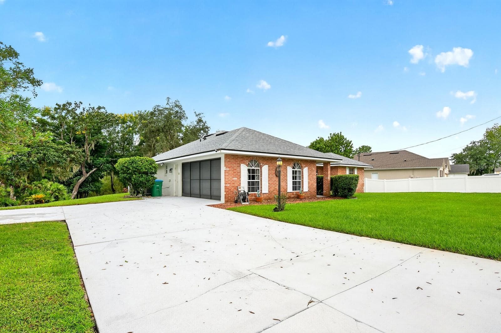 The OVERSIZED DRIVEWAY with turn-around, leads to a two-car garage featuring a SCREEN ENCLOSURE that allows the space to double as an extended hangout area or a place to enjoy the breeze. - 2163 NEWMARK DR, DELTONA