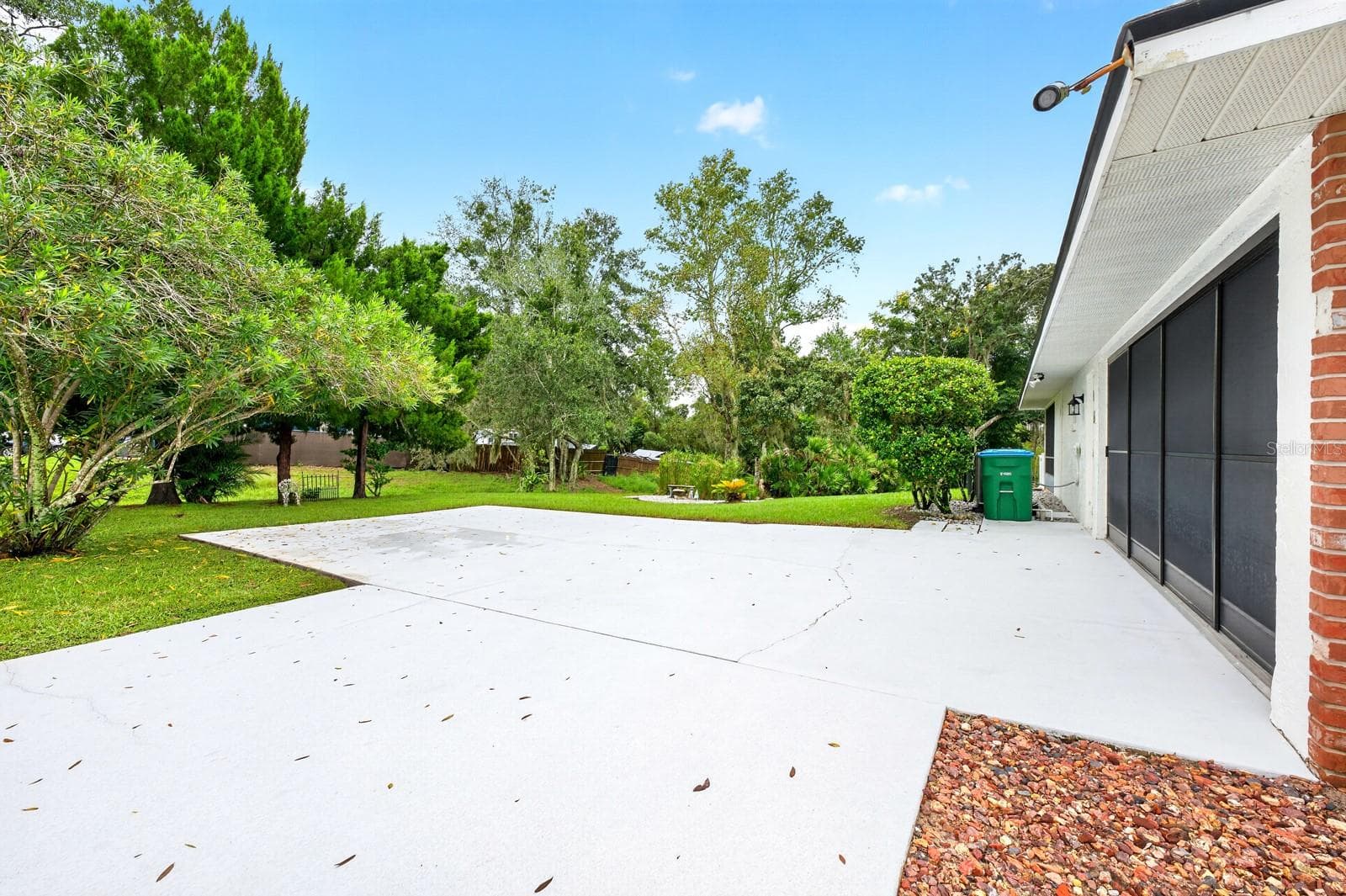 The OVERSIZED DRIVEWAY with turn-around, leads to a two-car garage featuring a SCREEN ENCLOSURE that allows the space to double as an extended hangout area or a place to enjoy the breeze. - 2163 NEWMARK DR, DELTONA