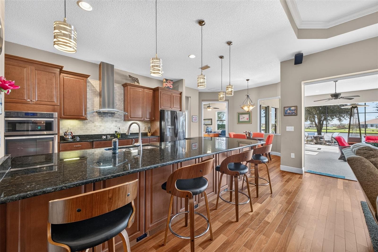 Durable granite countertops and rich wooden cabinetry elevate the kitchen, while a generous peninsula offers both extra storage and a welcoming spot for casual seating. - 2444 PAWTUCKET PASS, MOUNT DORA