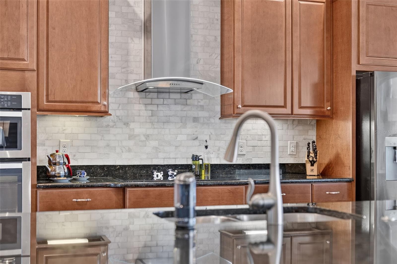 Rich wooden cabinetry, sleek granite countertops, and custom tilework make this gourmet kitchen an absolute chef’s dream. - 2444 PAWTUCKET PASS, MOUNT DORA