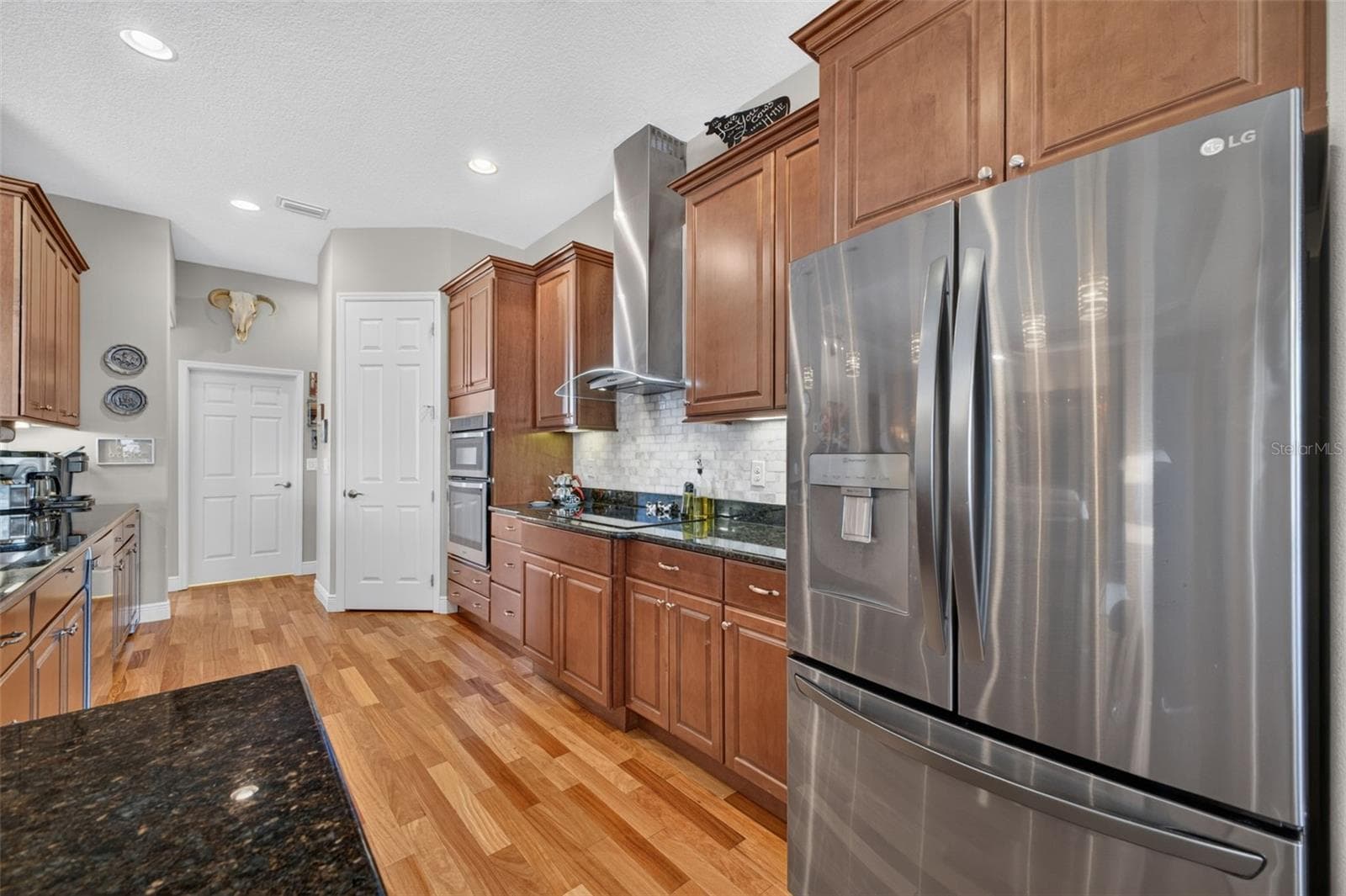 Warm wood floors, sleek stainless steel appliances, and built-in convection microwave and oven units make this kitchen a chef's dream for culinary creations. - 2444 PAWTUCKET PASS, MOUNT DORA