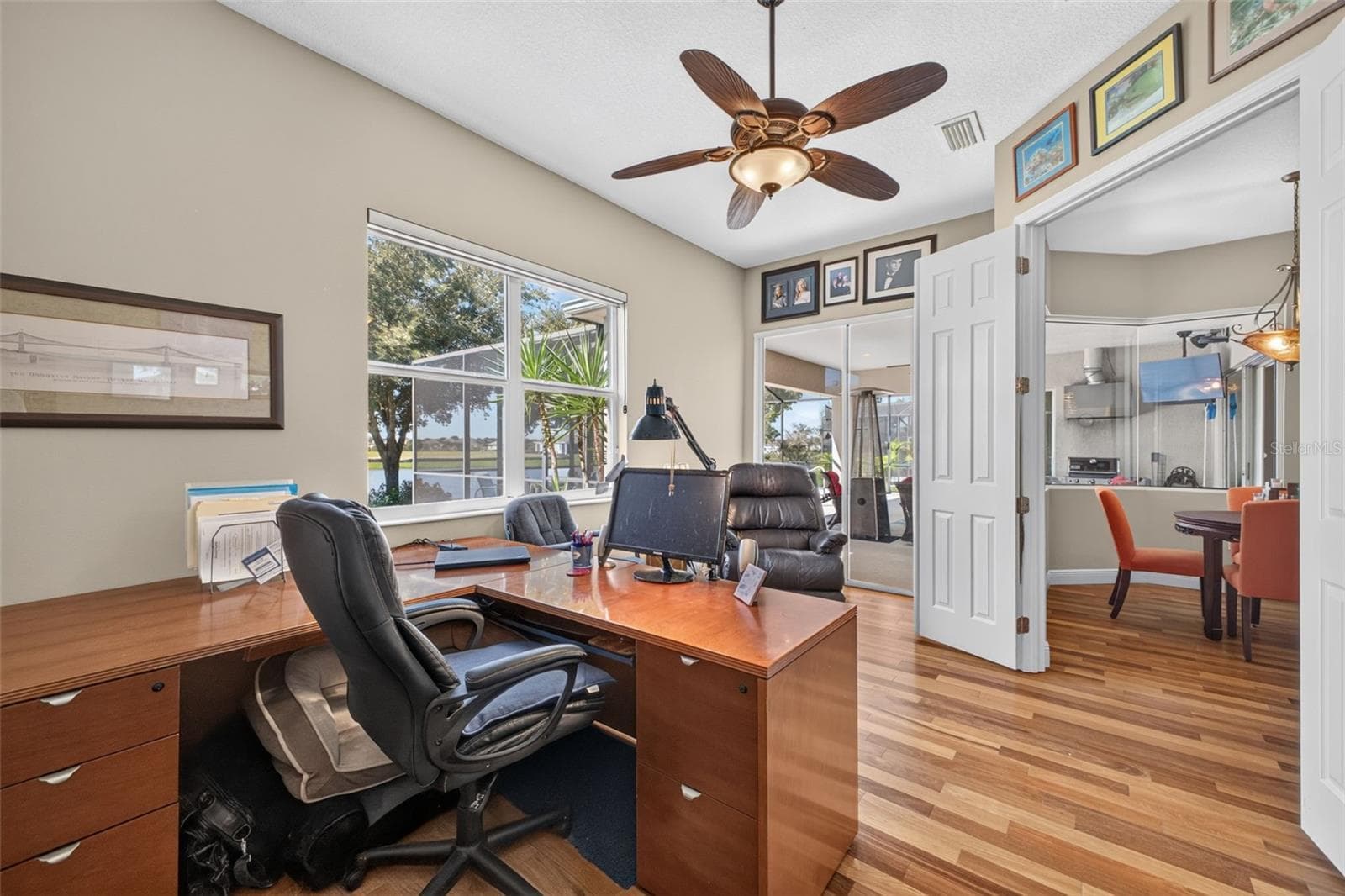 Framed by serene lake views, this dedicated home office features sliding glass doors that step directly out onto the lanai for an inspiring indoor-outdoor workspace. - 2444 PAWTUCKET PASS, MOUNT DORA