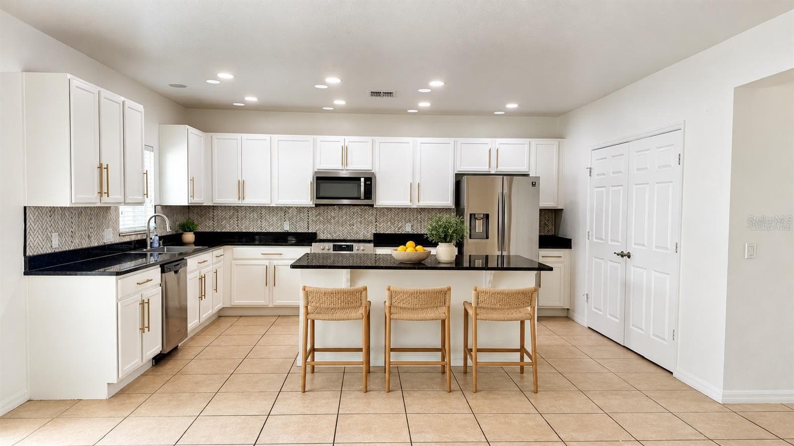 Virtually staged - Kitchen with existing island. Digital stools and countertop decor; original cabinets, appliances and finishes retained. Original unstaged view included. - 2255 SHEBOYGAN PL, KISSIMMEE