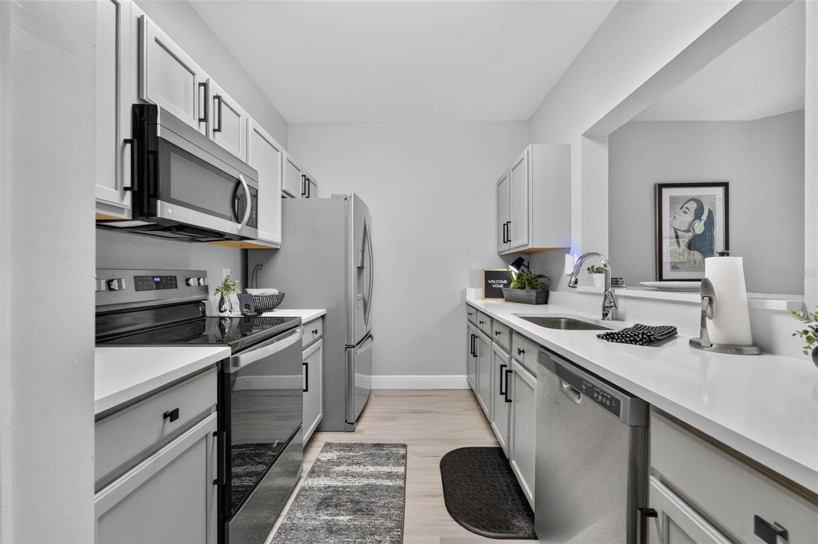 Kitchen with stainless appliances and white stone counters - 4849 CYPRESS WOODS DR #1302, ORLANDO