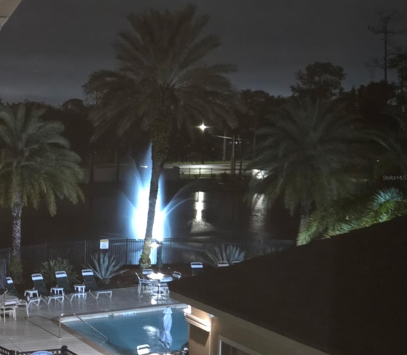 Night view of community pool and pond fountain from balcony - 4849 CYPRESS WOODS DR #1302, ORLANDO