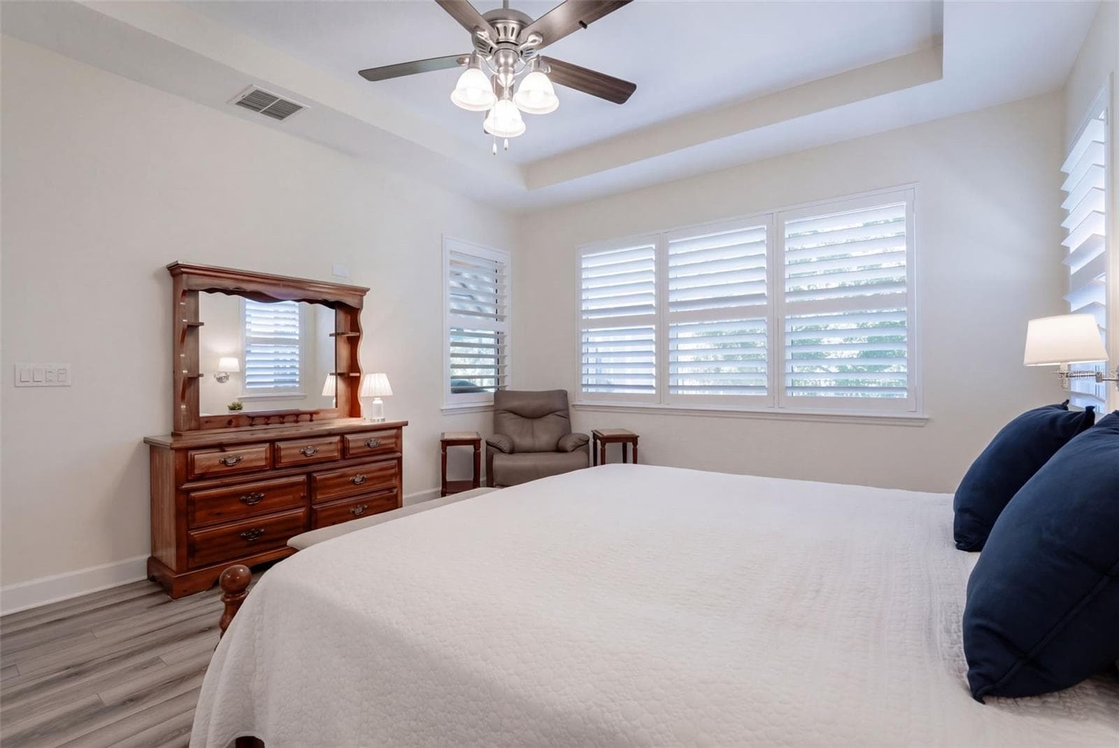 Primary Bedroom w/ Plantation style shutters, luxury vinyl floor, ceiling fan & a wooded view - 1233 EGGLESTON DRIVE, DELAND