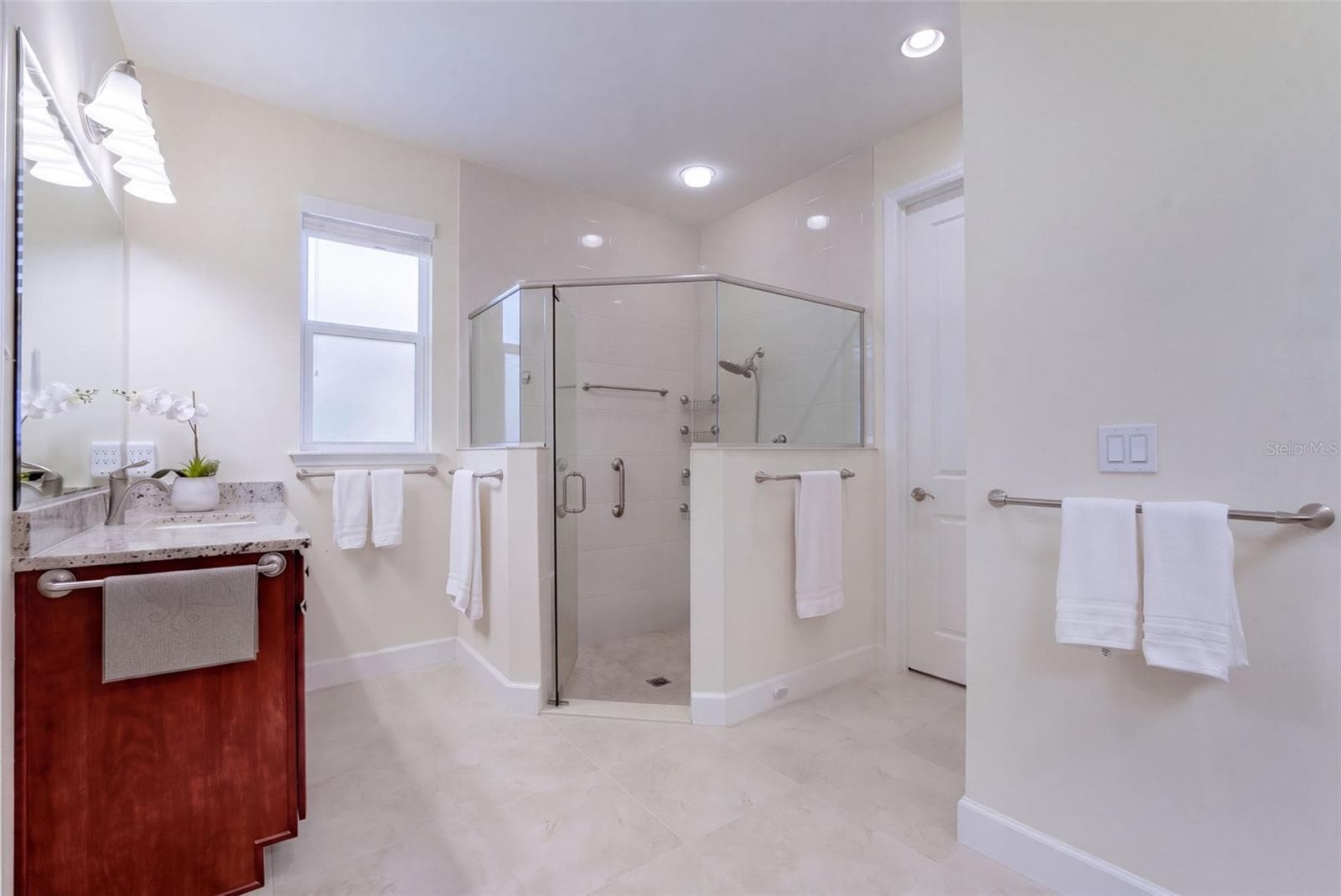 Primary Bathroom w/ separate granite vanities, glass enclosed walk-in shower, bench seat & a spacious walk-in closet - 1233 EGGLESTON DRIVE, DELAND