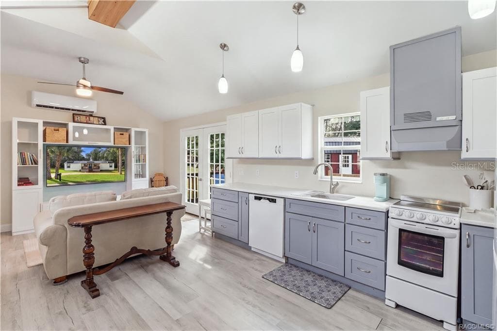 Kitchen & French Doors – Bright kitchen featuring white upper cabinetry, soft blue-gray lower cabinetry, SOLID SURFACE COUNTERTOPS & French doors leading to the outdoor deck. - 6230 W GLEN ROBBIN CT, CRYSTAL RIVER