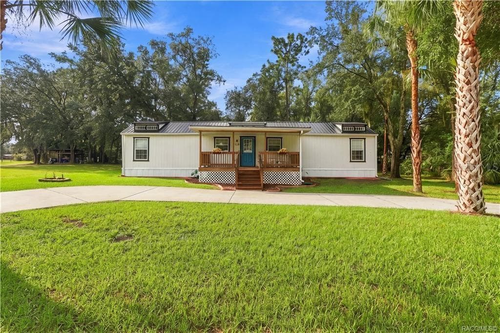 Charming Front Exterior – Beautifully presented home featuring a METAL ROOF, inviting COVERED FRONT PORCH, attractive landscaping & a welcoming blue front door. - 6230 W GLEN ROBBIN CT, CRYSTAL RIVER