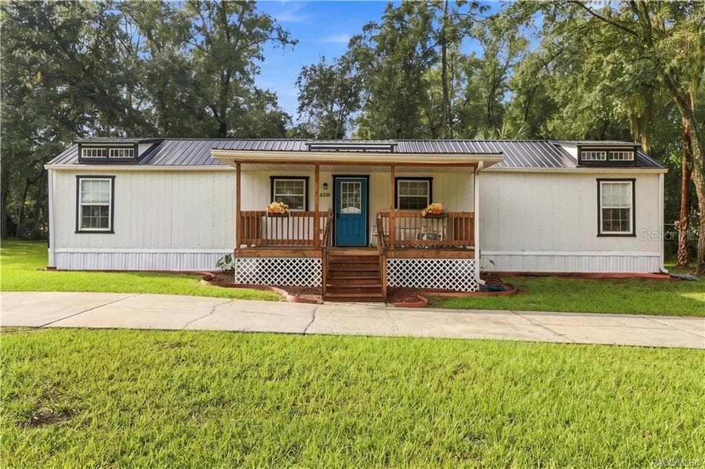Front Elevation – Enjoy the home's charming curb appeal, featuring a welcoming covered porch, wooden railings, decorative roof details & circular concrete driveway. - 6230 W GLEN ROBBIN CT, CRYSTAL RIVER