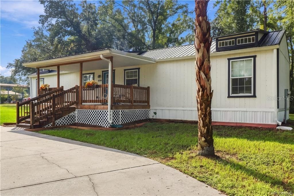 Exterior & Front Porch – Another inviting perspective highlighting the covered wooden porch, contrasting exterior finishes & beautiful palm tree. - 6230 W GLEN ROBBIN CT, CRYSTAL RIVER