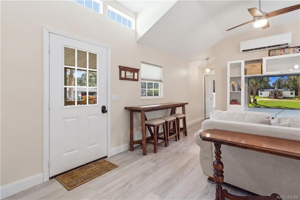Living Area & Front Entry – Welcoming living space featuring VAULTED CEILINGS, high transom windows, ceiling fan, attractive flooring & a convenient seating area near the front entrance. - 6230 W GLEN ROBBIN CT, CRYSTAL RIVER
