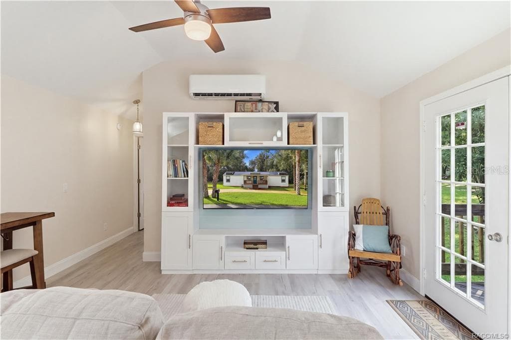 Living Room – Bright & inviting living room featuring VAULTED CEILINGS, luxury vinyl plank flooring, ceiling fan, w/entertainment cabinetry & a MINI-SPLIT HEATING & COOLING SYSTEM. French doors provide views of the backyard & access to the rear deck. - 6230 W GLEN ROBBIN CT, CRYSTAL RIVER