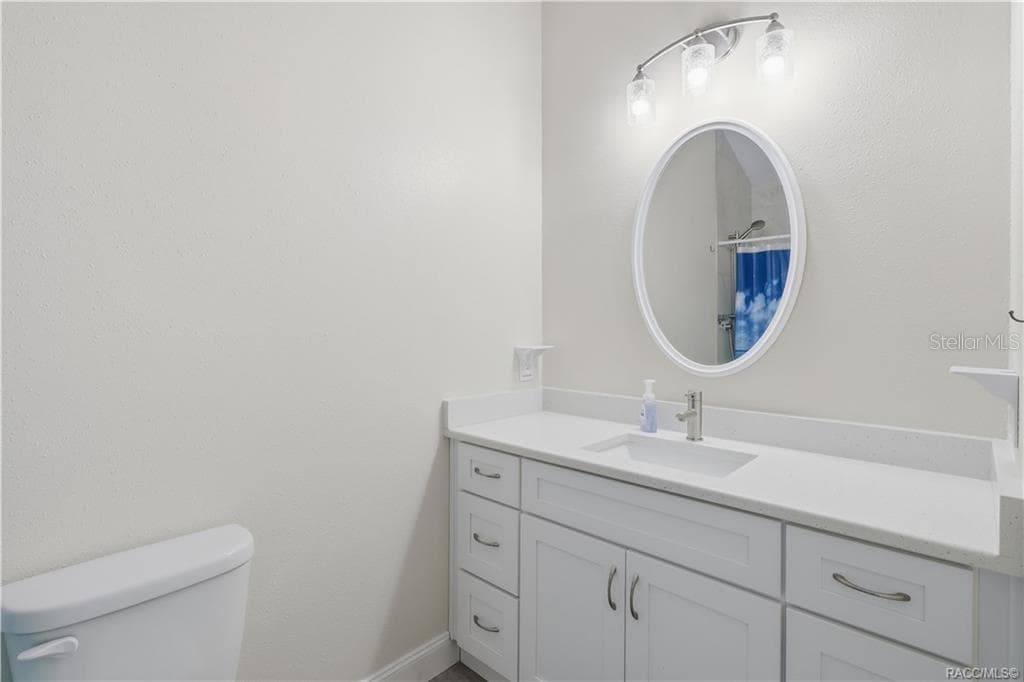 Primary Bathroom – Bright bathroom featuring a white vanity w/solid-surface countertop, undermount sink, oval mirror, attractive lighting & convenient storage cabinetry. - 6230 W GLEN ROBBIN CT, CRYSTAL RIVER