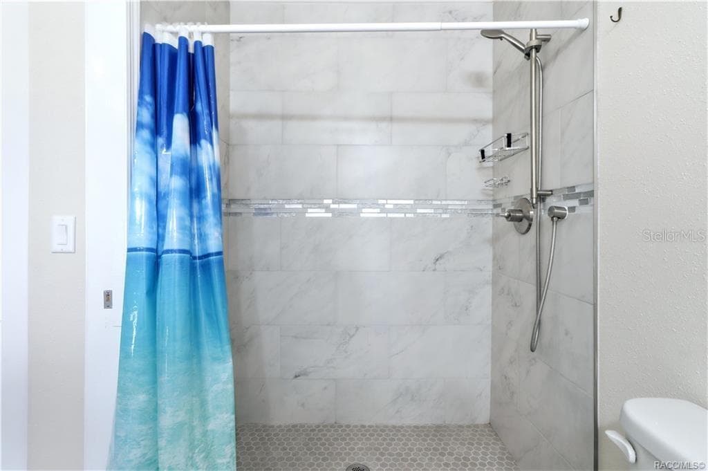 Primary Bathroom Shower – Beautifully tiled WALK-IN SHOWER featuring marble-look wall tile, decorative mosaic accent & handheld showerhead. - 6230 W GLEN ROBBIN CT, CRYSTAL RIVER