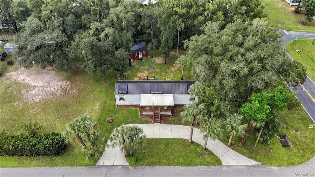 Aerial Property View – A beautiful overhead perspective of the .29-ACRE CORNER HOMESITE, showcasing the METAL ROOF, COVERED FRONT PORCH, circular concrete driveway, mature trees & detached storage building. - 6230 W GLEN ROBBIN CT, CRYSTAL RIVER