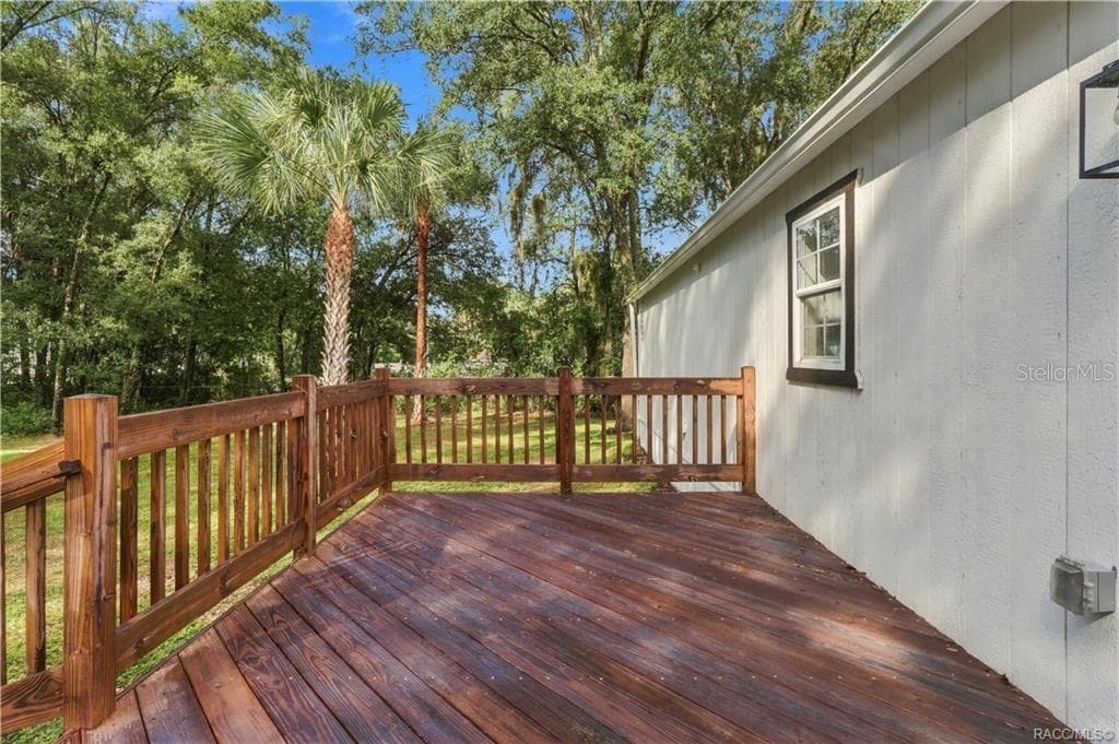 Rear Deck – Spacious wooden deck featuring sturdy railings & room for outdoor seating, surrounded by Florida greenery & mature palms. - 6230 W GLEN ROBBIN CT, CRYSTAL RIVER