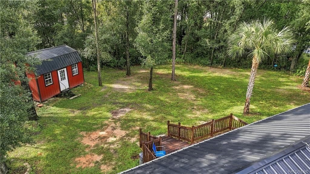 Aerial Backyard View – Enjoy the generous green space, mature shade trees, rear wooden deck & attractive red storage building that adds character to this inviting property. - 6230 W GLEN ROBBIN CT, CRYSTAL RIVER