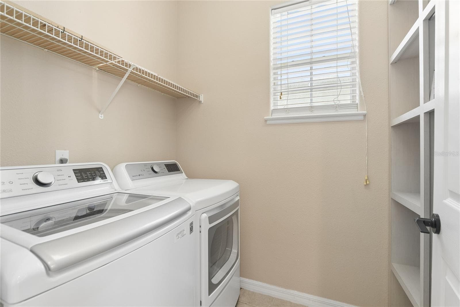 The laundry room that's right off the kitchen with a shelving unit to hold all your supplies. - 16169 BRISTOL LAKE CIR, ORLANDO