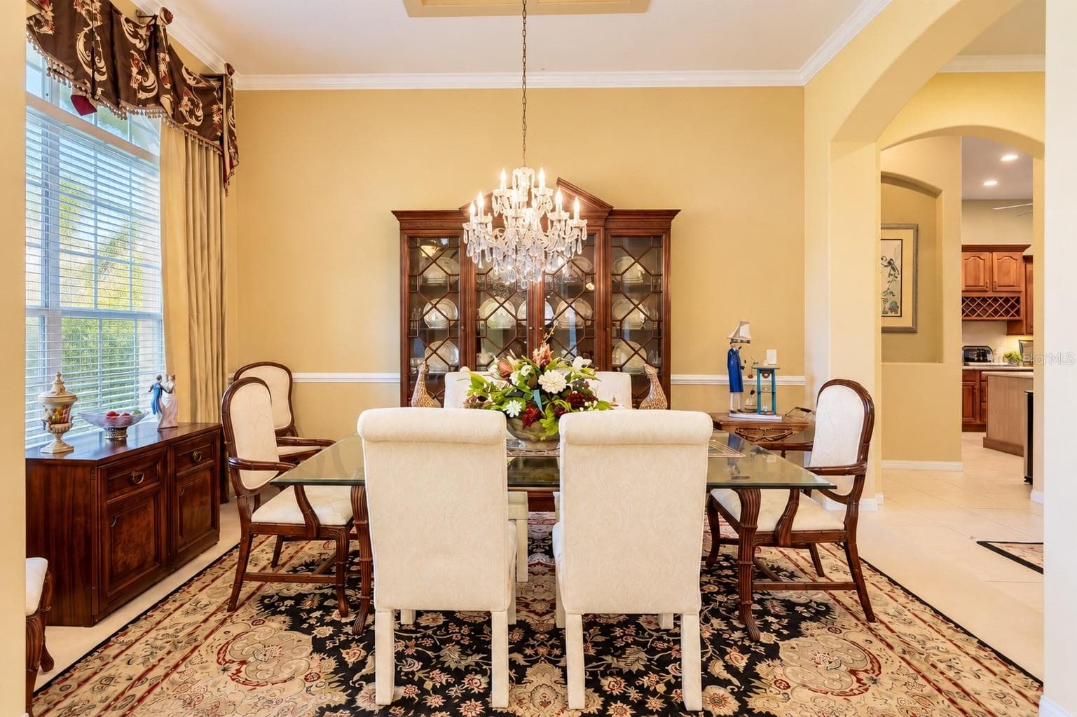 ELEGANT FORMAL DINING ROOM FEATURING SOARING CEILINGS, BEAUTIFUL CROWN MOLDING, and DECORATIVE CHAIR RAIL! A large window fills the room with natural light, while graceful architectural archways create an inviting flow to the kitchen, making this the perfect space for hosting holiday gatherings, special celebrations, and memorable dinners with family and friends! - 14542 RIVIERA POINTE DR, ORLANDO