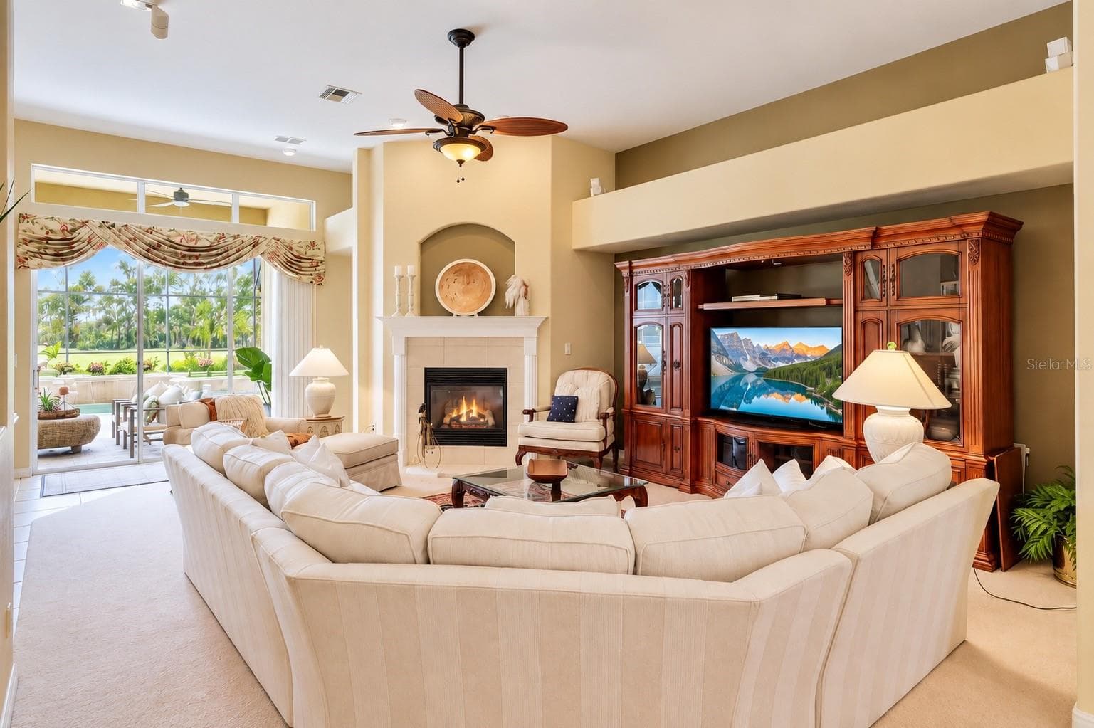 STUNNING, SPACIOUS FAMILY ROOM FEATURING SOARING CEILINGS, A BEAUTIFUL GAS FIREPLACE, ELEGANT ARCHITECTURAL DETAILS, AND ABUNDANT NATURAL LIGHT! Expansive sliding glass doors provide picturesque views of the sparkling pool and lush tropical landscaping while creating a seamless flow to the covered lanai. The perfect gathering space for cozy evenings by the fireplace, entertaining guests, and enjoying Florida's indoor-outdoor lifestyle! - 14542 RIVIERA POINTE DR, ORLANDO