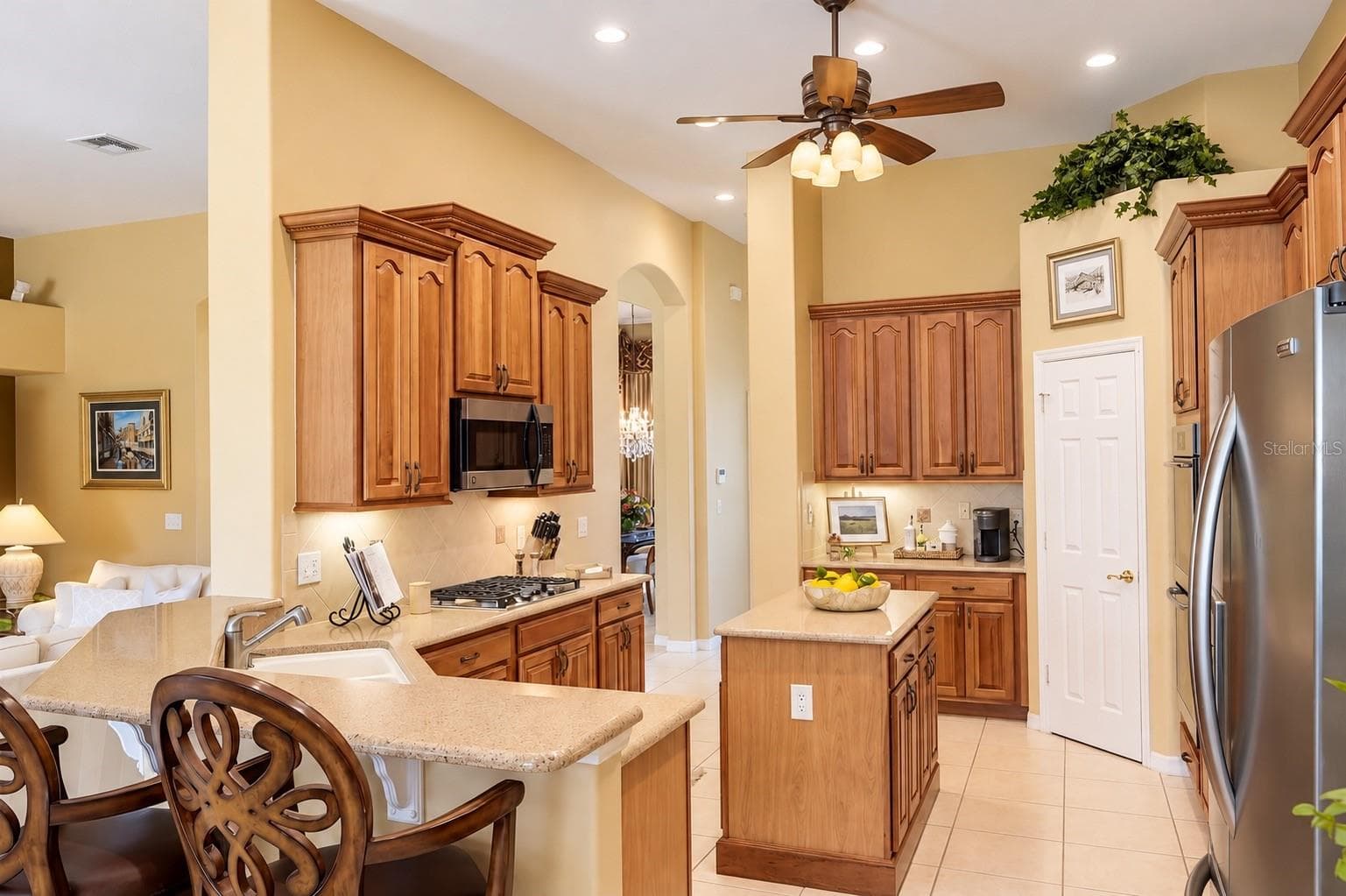 BEAUTIFULLY DESIGNED, SPACIOUS KITCHEN FEATURING SOARING CEILINGS, GORGEOUS WOOD CABINETRY, ABUNDANT COUNTER SPACE, AND STAINLESS STEEL APPLIANCES! Enjoy a CENTER ISLAND, BREAKFAST BAR WITH ADDITIONAL SEATING, GAS COOKTOP, UNDER-CABINET LIGHTING, AND RECESSED LIGHTING! - 14542 RIVIERA POINTE DR, ORLANDO