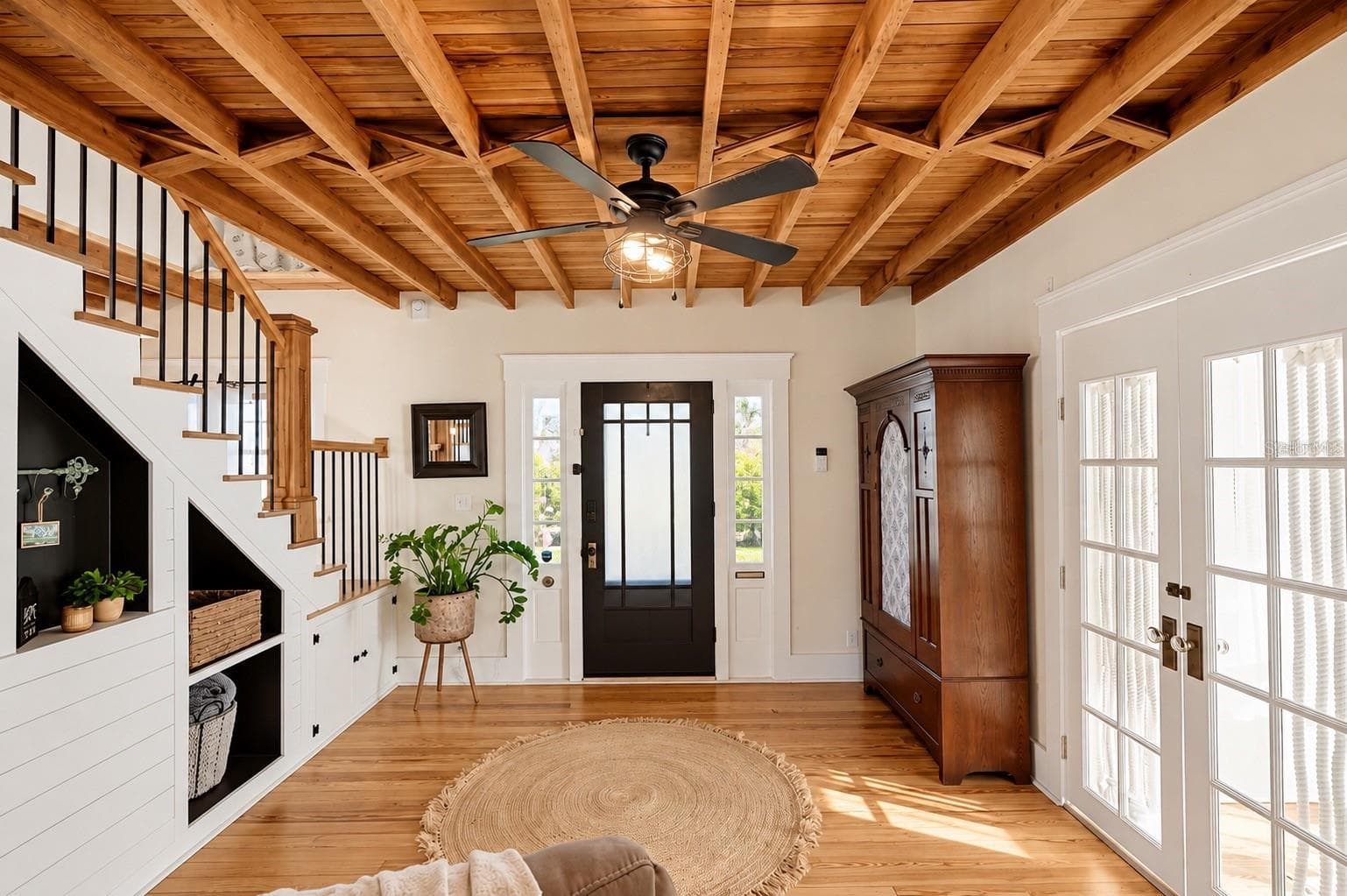 CHARMING ENTRYWAY featuring stunning EXPOSED WOOD BEAM CEILINGS, beautiful hardwood floors, a wooden staircase with black iron balusters, custom built-in shelving and storage, and French doors that fill the space with natural light. - 1901 10TH ST, ST CLOUD