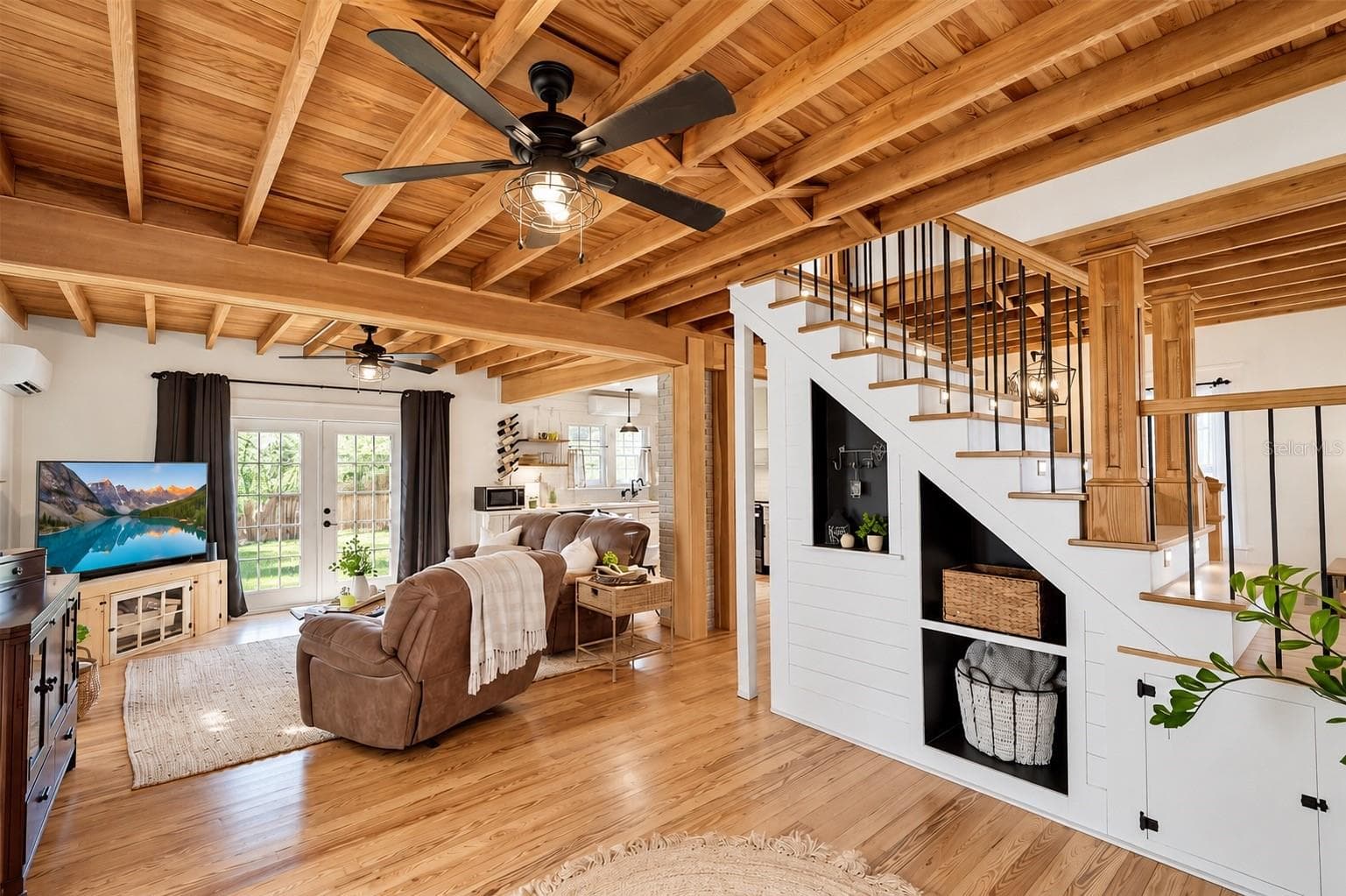 OPEN-CONCEPT LIVING SPACE featuring beautiful EXPOSED WOOD BEAM CEILINGS, hardwood floors, and custom BUILT-IN SHELVING AND STORAGE beneath the staircase. FRENCH DOORS provide abundant natural light and lead to the SPACIOUS, FULLY FENCED BACKYARD. The living area flows seamlessly into the OPEN KITCHEN, creating a wonderful space for everyday living and entertaining! - 1901 10TH ST, ST CLOUD
