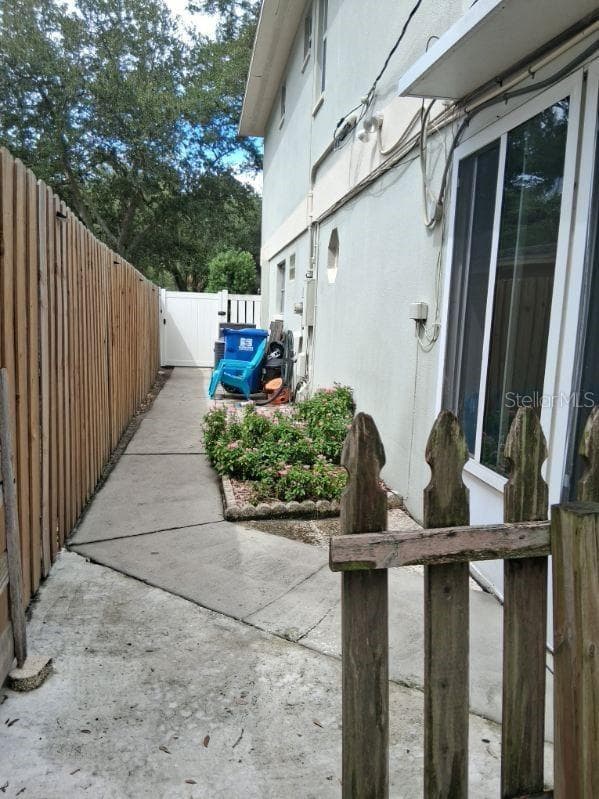 South side of home with vinyl gate to driveway, and man door into garage - 8220 YARDLEY AVE N, ST PETERSBURG