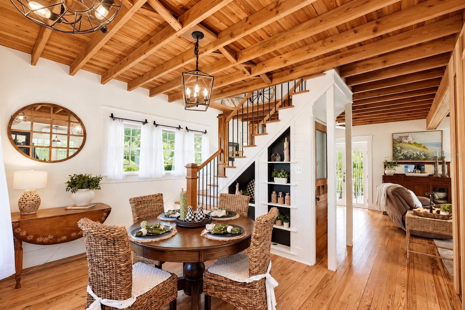 DINING AREA featuring stunning EXPOSED WOOD BEAM CEILINGS, beautiful WOOD FLOORING, stylish pendant lighting, and CUSTOM BUILT-IN SHELVING beneath the staircase. - 1901 10TH ST, ST CLOUD