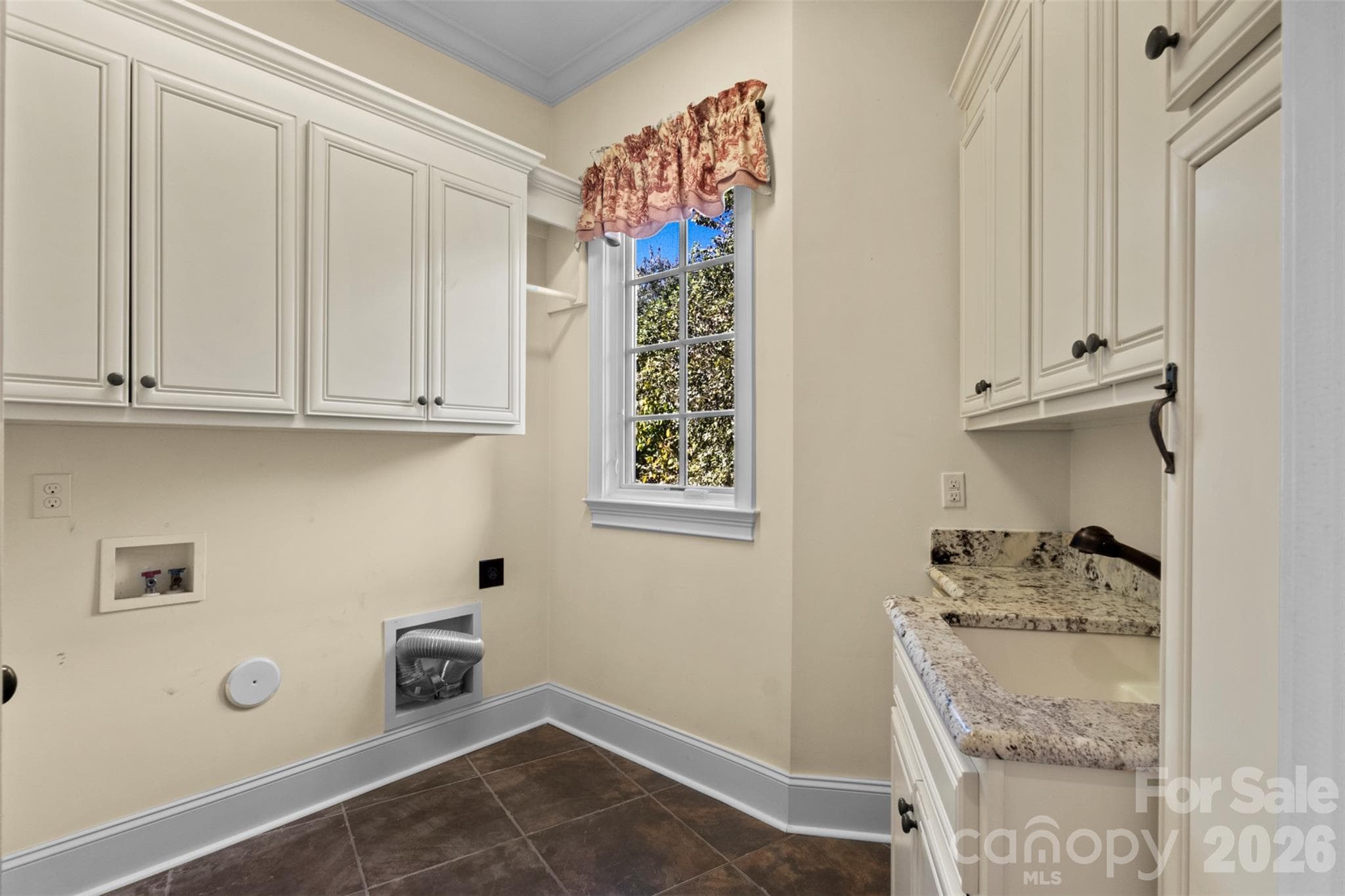 Laundry room off the garage with utility sink, cabinetry, and a wall mounted ironing board - 973 Pinnacle Drive, Iron Station