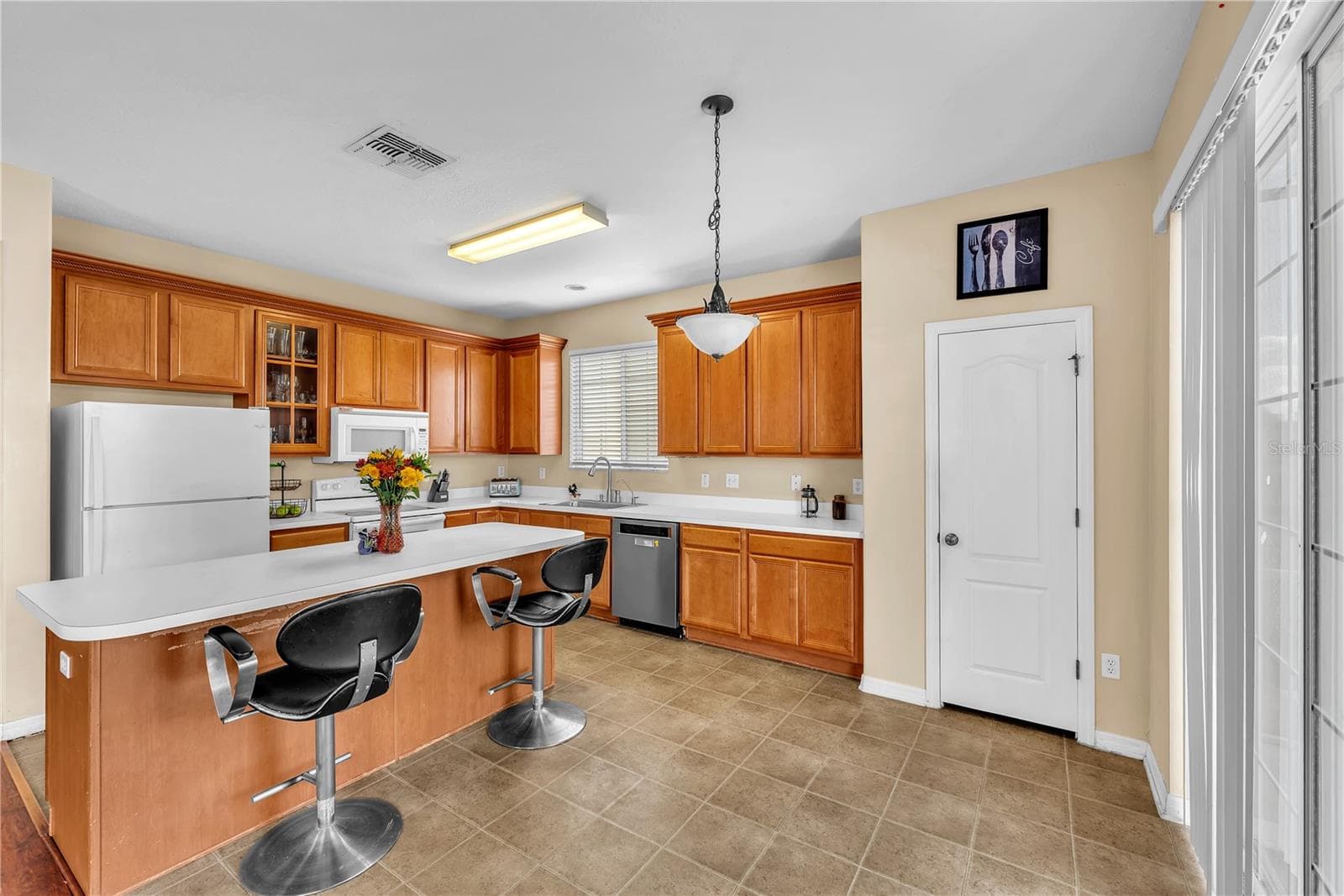 At the heart of the home is a huge kitchen featuring an oversized island with breakfast bar seating, abundant workspace, and plenty of room for gathering. - 18801 SUNTERRA DR, LAND O LAKES