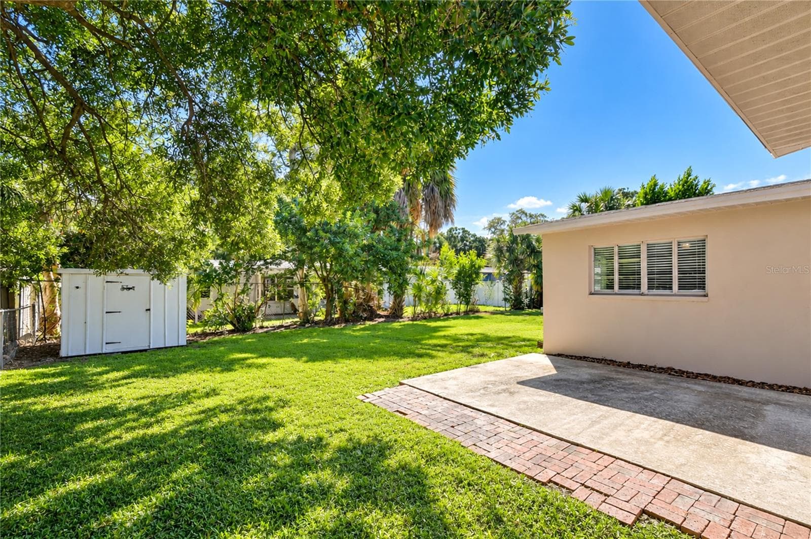 Private backyard featuring a lush lawn, outdoor space for entertaining, and a convenient detached storage shed. - 4508 S LOIS AVE, TAMPA