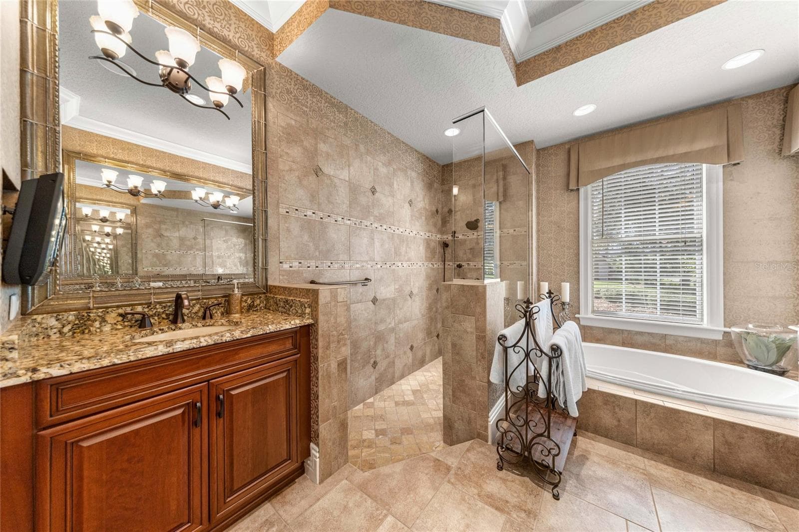 Spa-inspired owner's bathroom featuring a beautifully tiled walk-in shower, soaking tub, and elegant finishes. - 6501 SW 179TH AVENUE RD, DUNNELLON