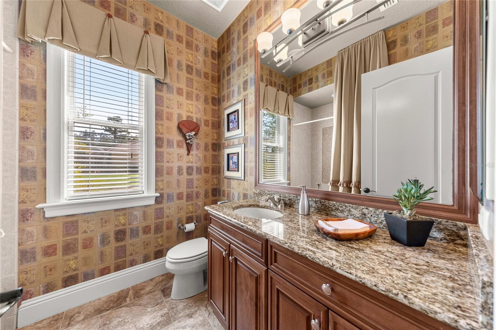 Attractive bathroom featuring granite countertops, wood cabinetry, decorative wall finishes, and natural light. - 6501 SW 179TH AVENUE RD, DUNNELLON
