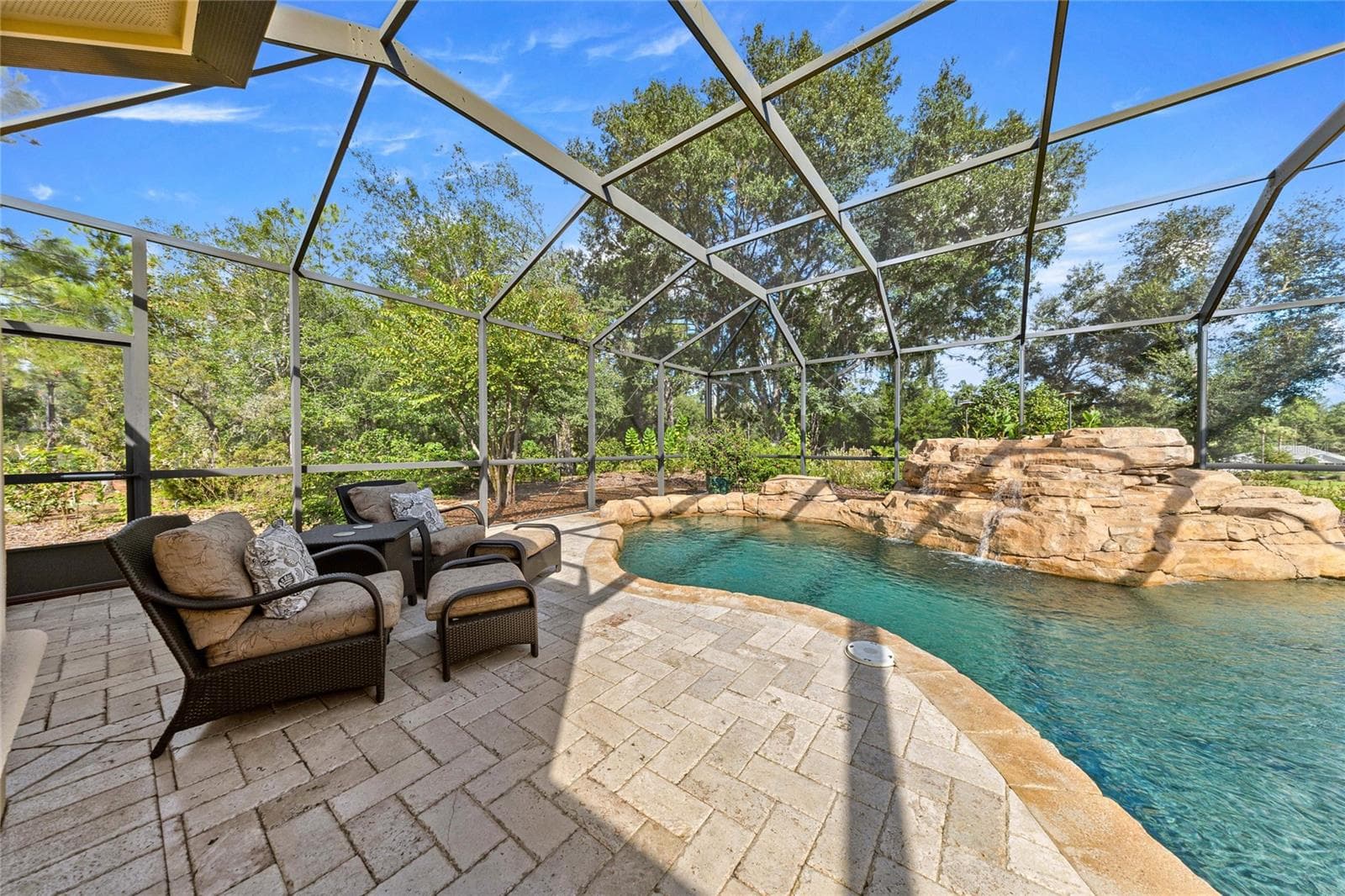 Your private backyard retreat! Custom-designed pool with cascading rock waterfall, natural stone accents, and expansive paver decking. - 6501 SW 179TH AVENUE RD, DUNNELLON
