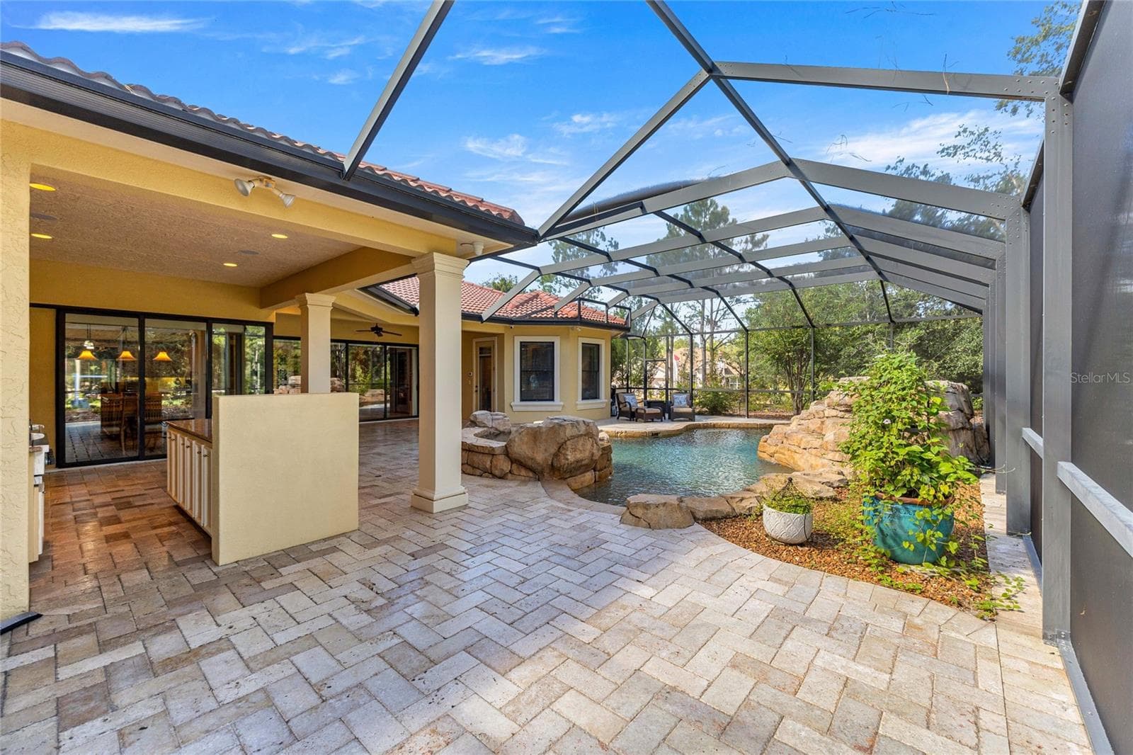 Expansive covered lanai with brick pavers, ceiling fan, and views of the custom pool and spa. - 6501 SW 179TH AVENUE RD, DUNNELLON