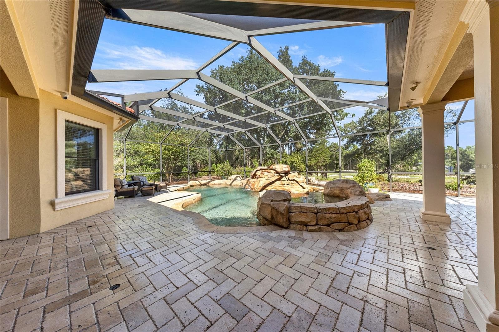 Resort-style outdoor retreat featuring a custom pool, raised spa, screened enclosure, and covered entertaining area. - 6501 SW 179TH AVENUE RD, DUNNELLON
