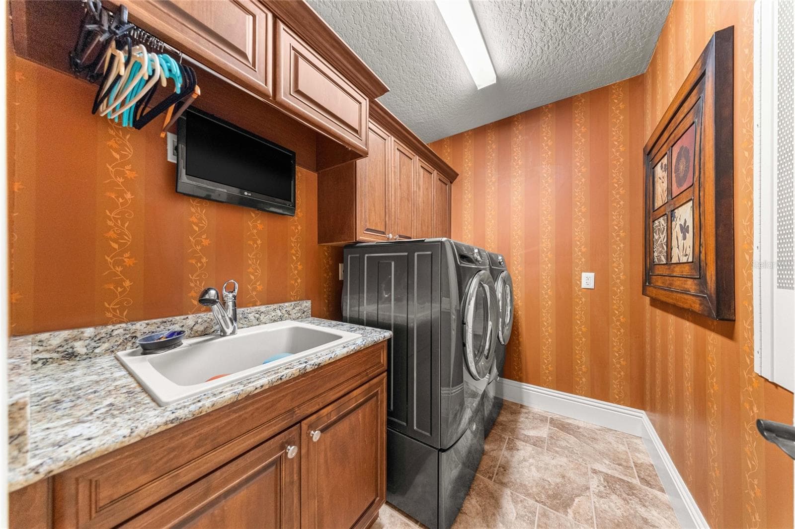 Laundry Room – Built-in wood cabinetry, granite countertop, utility sink, and washer and dryer. - 6501 SW 179TH AVENUE RD, DUNNELLON