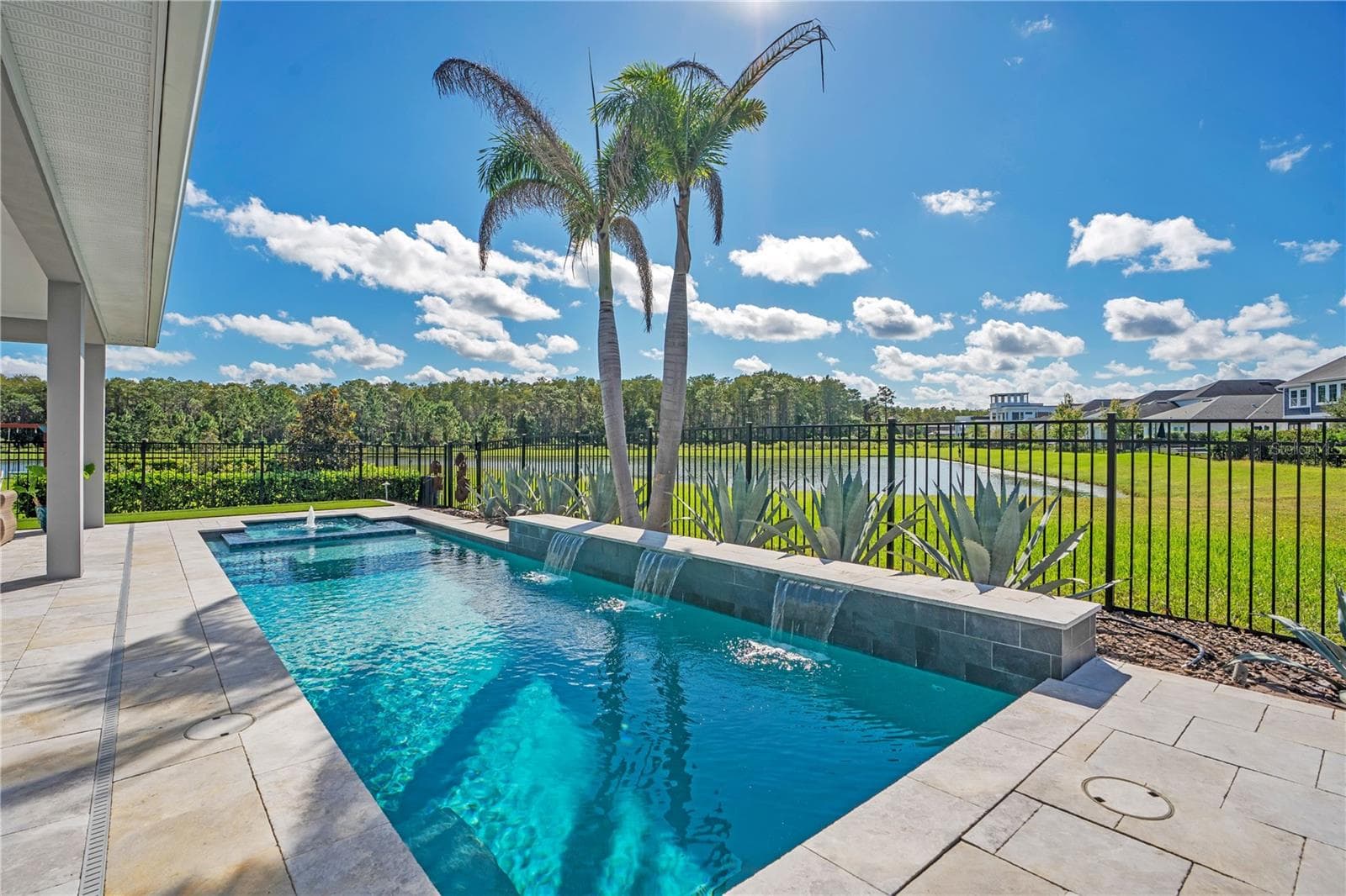 Private heated salt water pool framed by palms and a fenced yard with a water and conservation view. Lake Nona pool home living in Laureate Park, Orlando. - 8336 CANETTI ST, ORLANDO