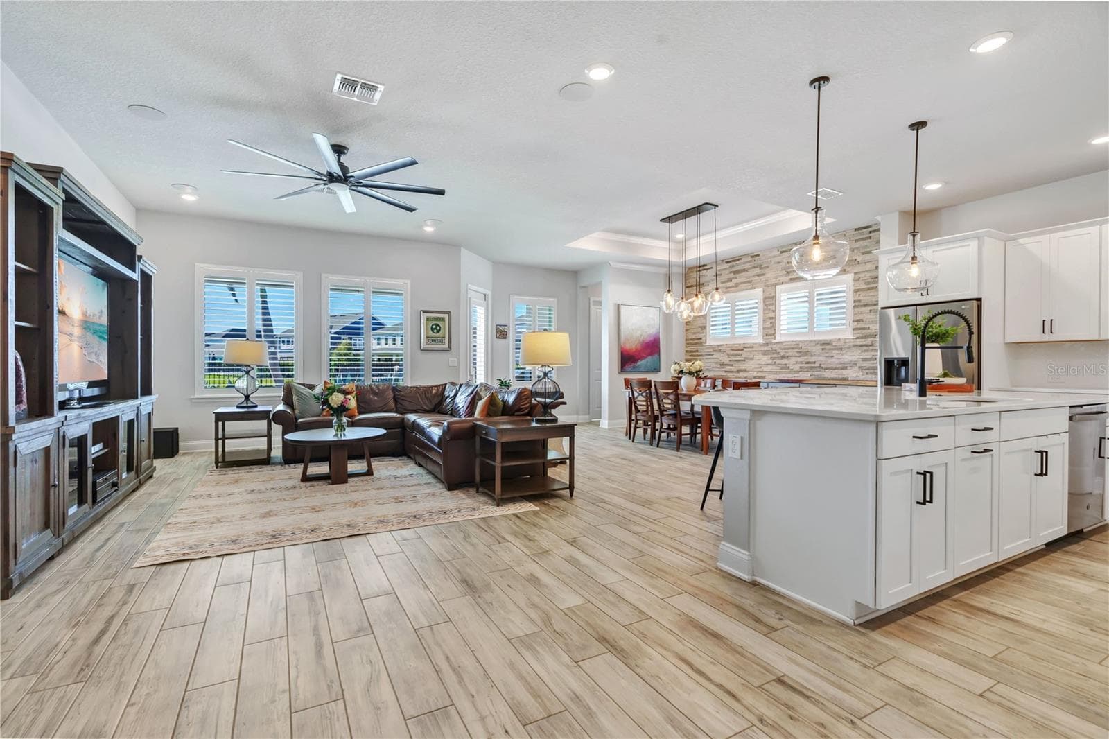 Open floor plan connecting the great room, kitchen, and dining area. Wood look plank tile, crown moulding, and natural light throughout this one story Lake Nona home. - 8336 CANETTI ST, ORLANDO