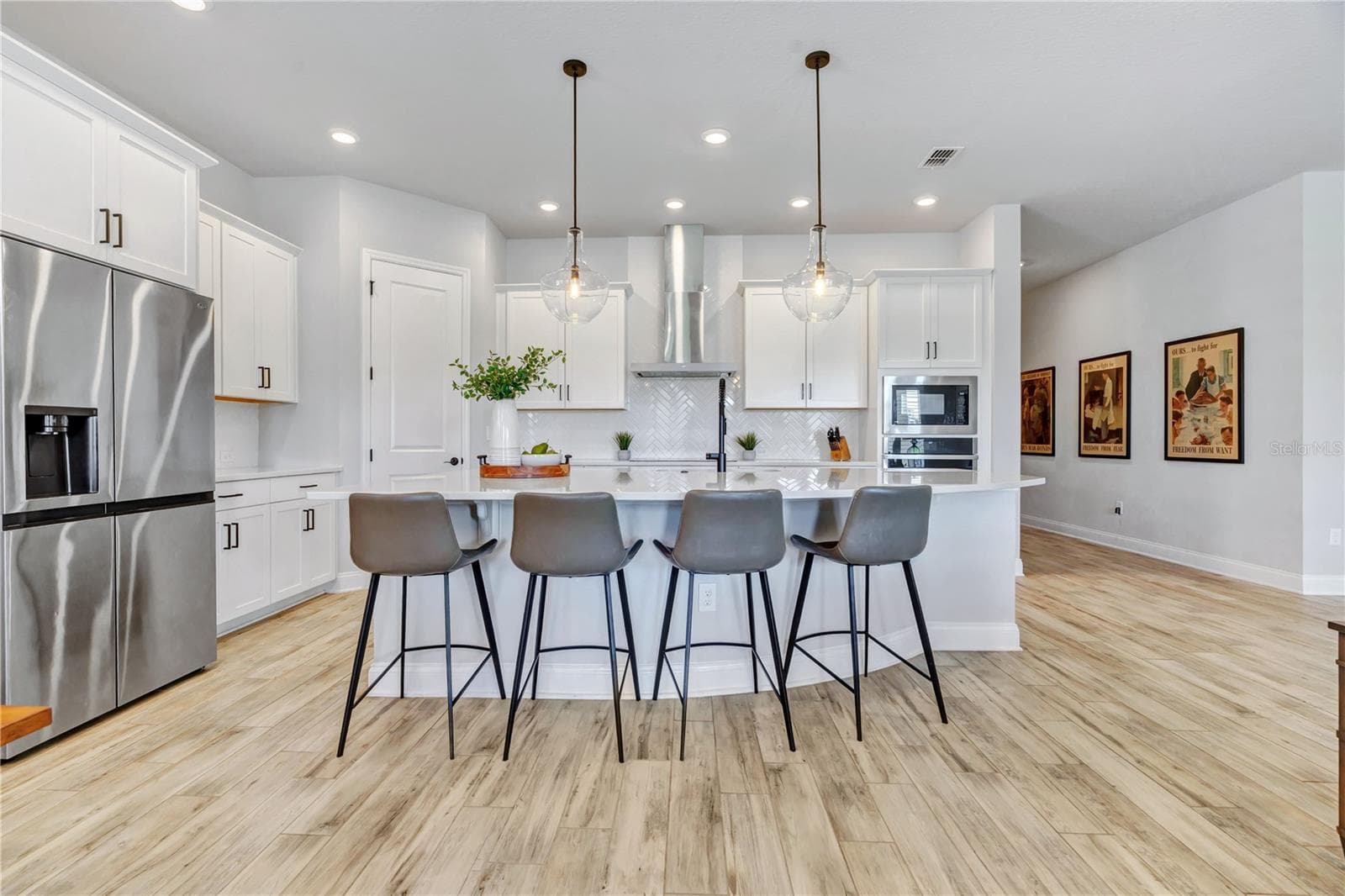 Chef inspired kitchen with an expansive Calacatta Arno quartz island, seating for four, statement pendants, stainless appliances, and a built in wall oven and microwave. - 8336 CANETTI ST, ORLANDO
