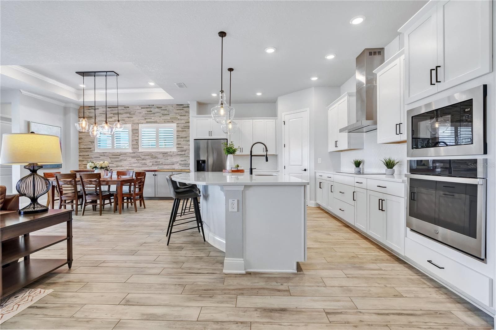 Kitchen view from the great room showing the oversized quartz island, 42 inch cabinetry, wall oven, and microwave. - 8336 CANETTI ST, ORLANDO